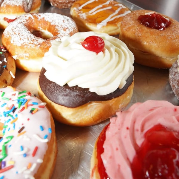Assortment of colorful donuts with various toppings including sprinkles, frosting, and fruit fillings.