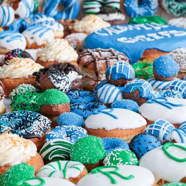 A vibrant assortment of blue, green, and white frosted donuts with various sprinkles and designs.