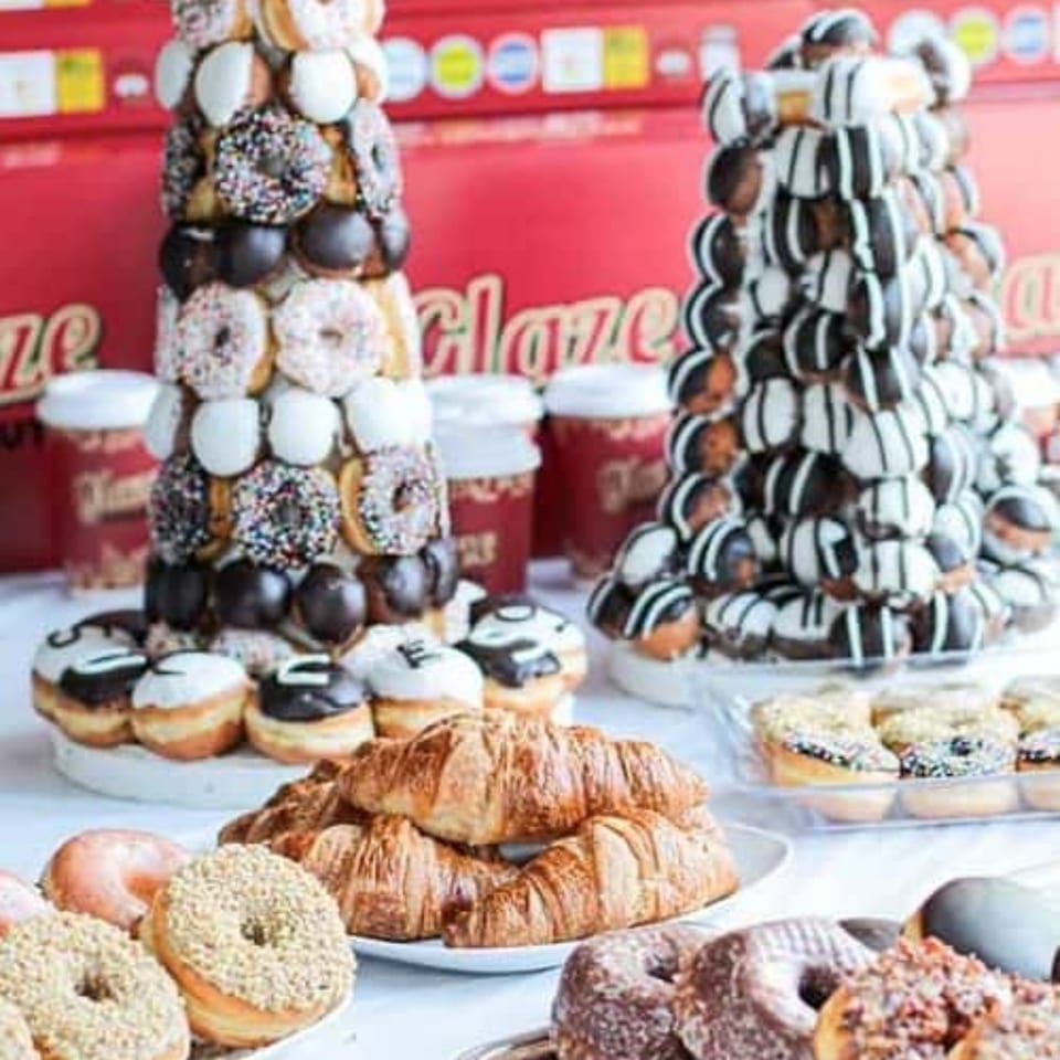 Two donut towers, croissants, and various donuts and pastries on a white table.