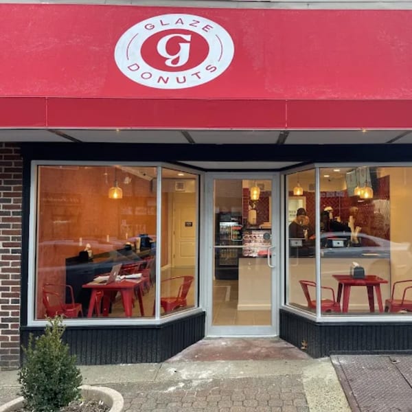 Exterior view of Glaze Donuts storefront with a red awning and visible interior seating.